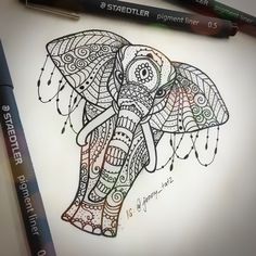 a drawing of an elephant with intricate patterns on it's body and head, sitting next to two markers