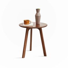 a small table with a vase and cup on it, sitting next to each other