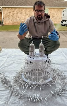 a man sitting on top of a white birdcage