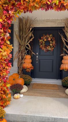 a front door decorated for fall with pumpkins and flowers