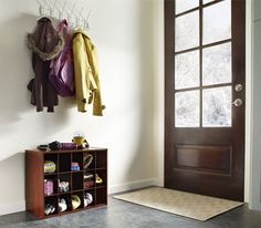 a coat rack is next to a door in a room with gray tile flooring