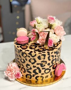 a leopard print cake with pink and white flowers on the top, sitting on a table