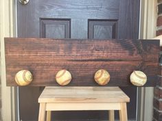 three baseballs are mounted to a wooden board on the front door step next to a stool