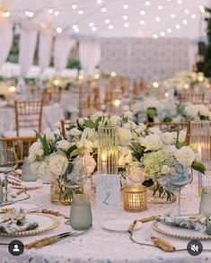 a table set up with white flowers and candles for an elegant wedding reception at the park