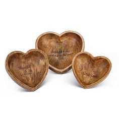 three wooden heart shaped bowls with engraved words on the sides and hearts in the middle