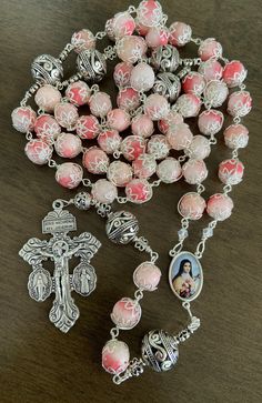 "This beautiful handmade rosary is made with 10mm pink stone,silver plated beads, 2\" Pardon crucifix. Length: 28\" inches long" Handmade Pink Rosary With Round Beads, Pink Beaded Spiritual Rosary, Pink Rosary With Miraculous Medal As A Gift, Pink Rosary With 8mm Round Beads, Pink Rosary With 8mm Beads For Gift, Pink Rosary With 8mm Beads As Gift, Pink Spiritual Rosary Bracelet With 8mm Beads, Pink 8mm Bead Spiritual Rosary Bracelet, Handmade Pink Spiritual Rosary