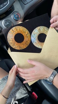 two people are holding up some paper with eyeballs on it