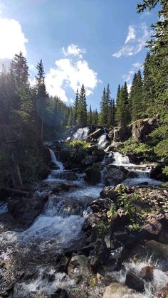 the sun shines brightly on a small waterfall in the woods near some rocks and trees