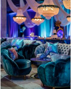 a room filled with blue velvet couches and chandeliers