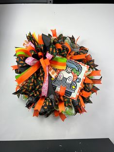 a halloween wreath is hanging on the wall with orange and black ribbon around it,