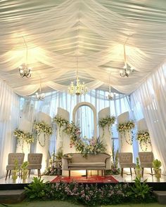 a room decorated with flowers and greenery on the ceiling, along with white drapes