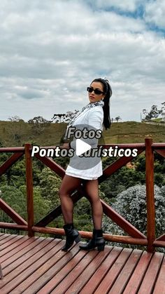 a woman standing on top of a wooden bridge