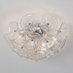 a light fixture with clear glass petals and lights in the center, on a white background