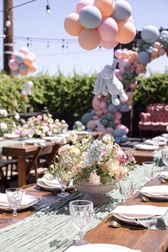 a table set with plates, silverware and balloons