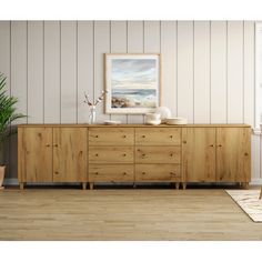 an empty room with a large wooden dresser and potted plant on the sideboard