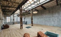 an empty room with wooden floors and exposed ceilings, leather couches in the middle