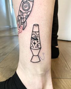 a tattoo on the leg of a woman with a rocket ship and vase in it