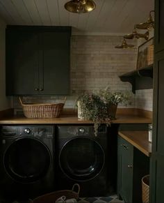 a washer and dryer in a small room with green cabinets, wood flooring and hanging lights