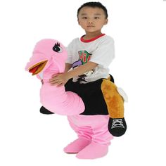 a young boy riding on the back of a pink dinosaur stuffed animal with big eyes