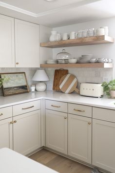 a kitchen with white cabinets and open shelving above the countertop is filled with dishes