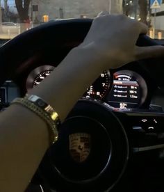 a person driving a car at night with their hand on the steering wheel while wearing bracelets