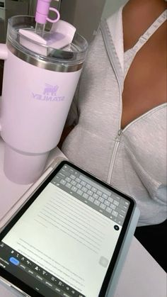 a woman holding a tablet next to a pink coffee cup and blender on a table