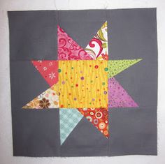 a quilted star is hanging on the wall next to a white wall with a gray background