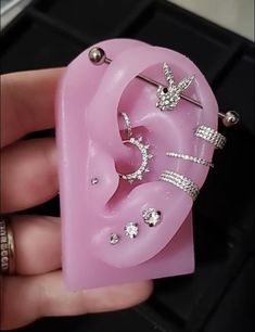 a person holding a pink heart shaped brooch with jewelry on it's side