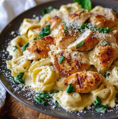 pasta with chicken, spinach and parmesan cheese in a bowl on a wooden table