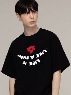 a young man wearing a black t - shirt with red flowers on it