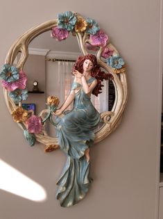 a mirror with a statue of a woman holding flowers in the shape of a circle