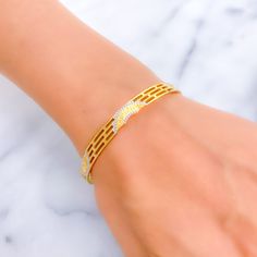 This 22k gold bangle, with a weight of 16.0 grams, captivates with its gorgeous semi-circle adornments in a harmonious blend of yellow and white gold. The design adds a geometric elegance to the bangle, enhancing its visual appeal. Sized at 2.6 and featuring a bangle opening of 2.35 inches, it ensures a snug yet comfortable fit. This singular piece is a testament to exquisite design and craftsmanship, ideal for those who seek jewelry that combines classic elements with a modern twist. It's a striking accessory that adds sophistication to any outfit, embodying luxury and style. PRODUCT DETAILS Gold Purity(karat): 22k Gold Weight(grams): 16.0 Item Finish: Yellow + White Gold Size: 2.6 Bangle Opening: ﻿2.35" Number Of Pieces: 1 Bangle Style No - VP068 Modern Gold Bangle Bracelet With Diamond Cut, Modern Gold Bangle With Diamond Cut, Modern Gold Diamond Cut Bangle, Modern Yellow Gold Diamond Cut Bangle, 22k Gold Bangles, Bangles Style, Gold Bangle, 22k Gold, Gold Bangles