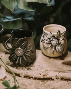 three ceramic vases sitting on top of a wooden table next to leaves and flowers