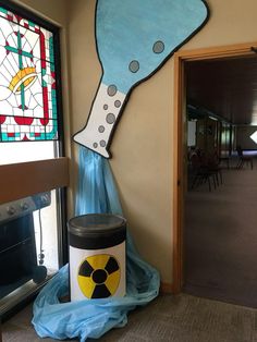 a trash can sitting in front of a window next to a stained glass wall mural