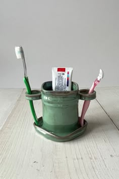 a toothbrush holder with toothpaste and toothbrushes in it