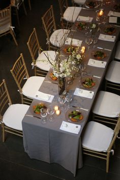 a long table set with place settings and flowers