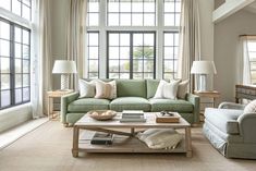 a living room with two couches and a coffee table in front of large windows