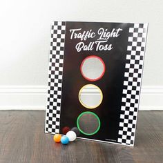 a traffic light with three balls on the ground next to it and a sign that says traffic light pull toss