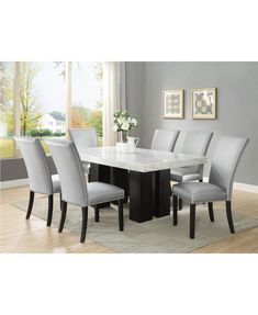 a dining room table with grey chairs and a white rug in front of the window