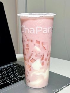 a pink drink sitting on top of a laptop computer next to a cup filled with ice cream