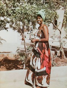 a woman standing next to a tree in front of a building