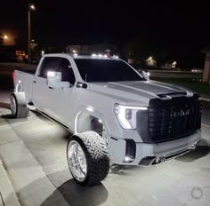 a white truck parked on the side of a road at night with its lights on