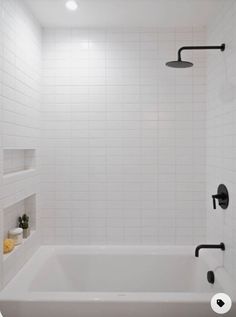 a white tiled bathroom with black fixtures and no shower head or faucet in it