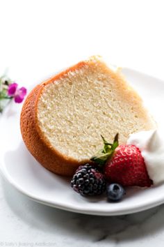 a slice of pound cake on a plate with berries and whipped cream next to it