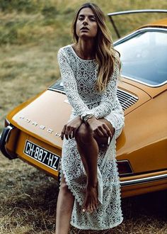 a woman sitting on the hood of an orange sports car