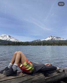 a man laying on top of a wooden dock next to a lake