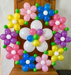 a bunch of balloons that are in the shape of flowers on a table with a door behind them