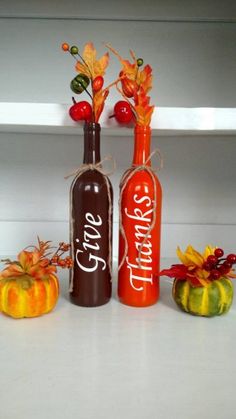 two wine bottles decorated with fall leaves and pumpkins are sitting next to each other