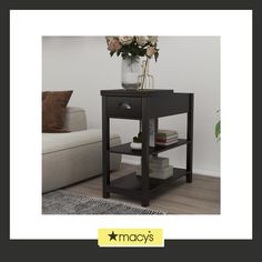 a black end table with flowers in a vase on top