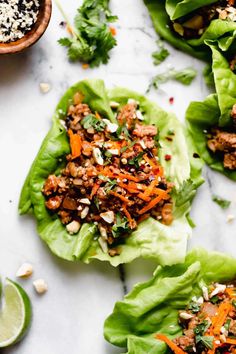 lettuce wraps filled with meat, carrots and seasoning on a marble surface